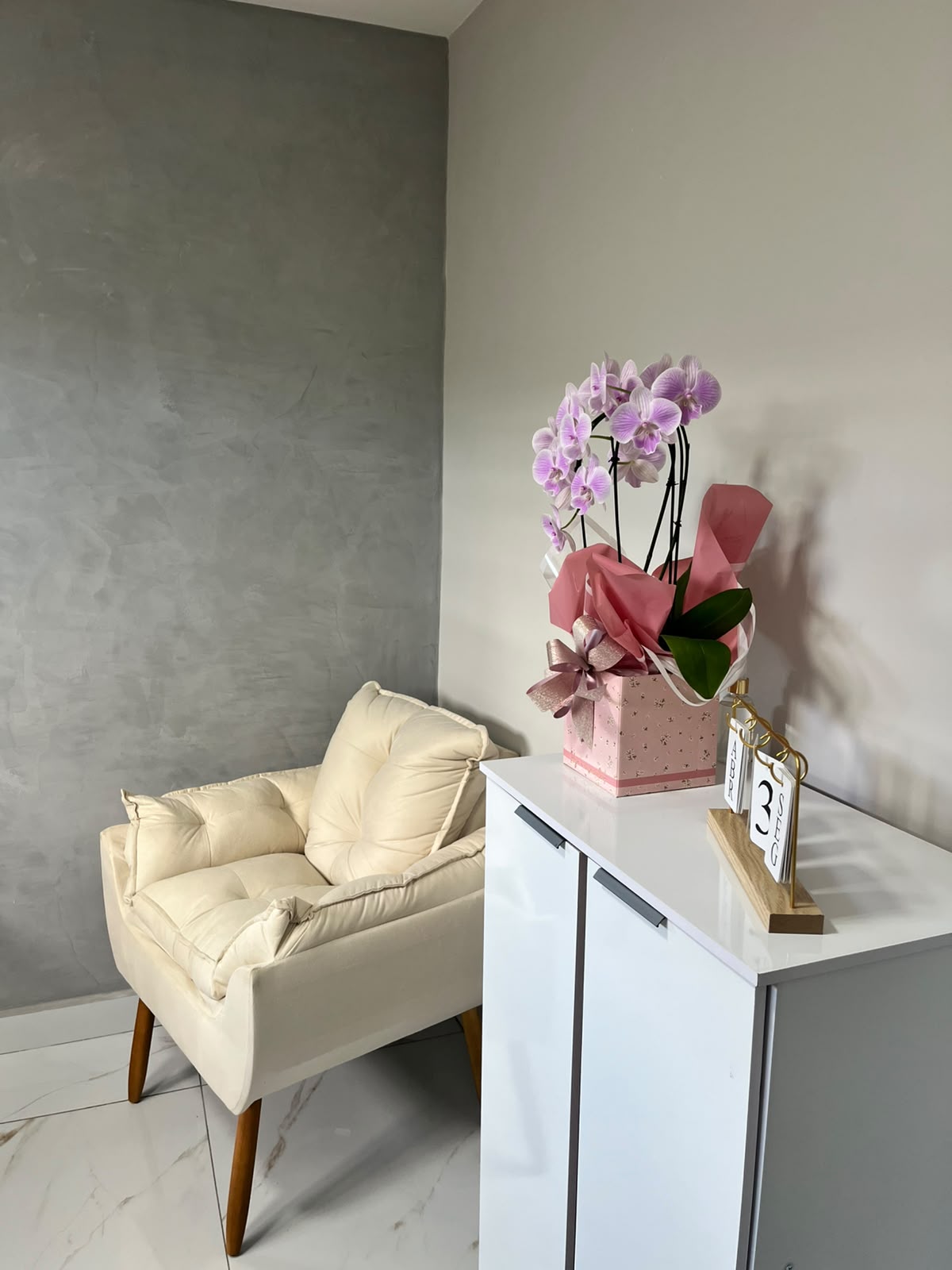 Poltrona clara e orquídea sobre o armário da sala de atendimento