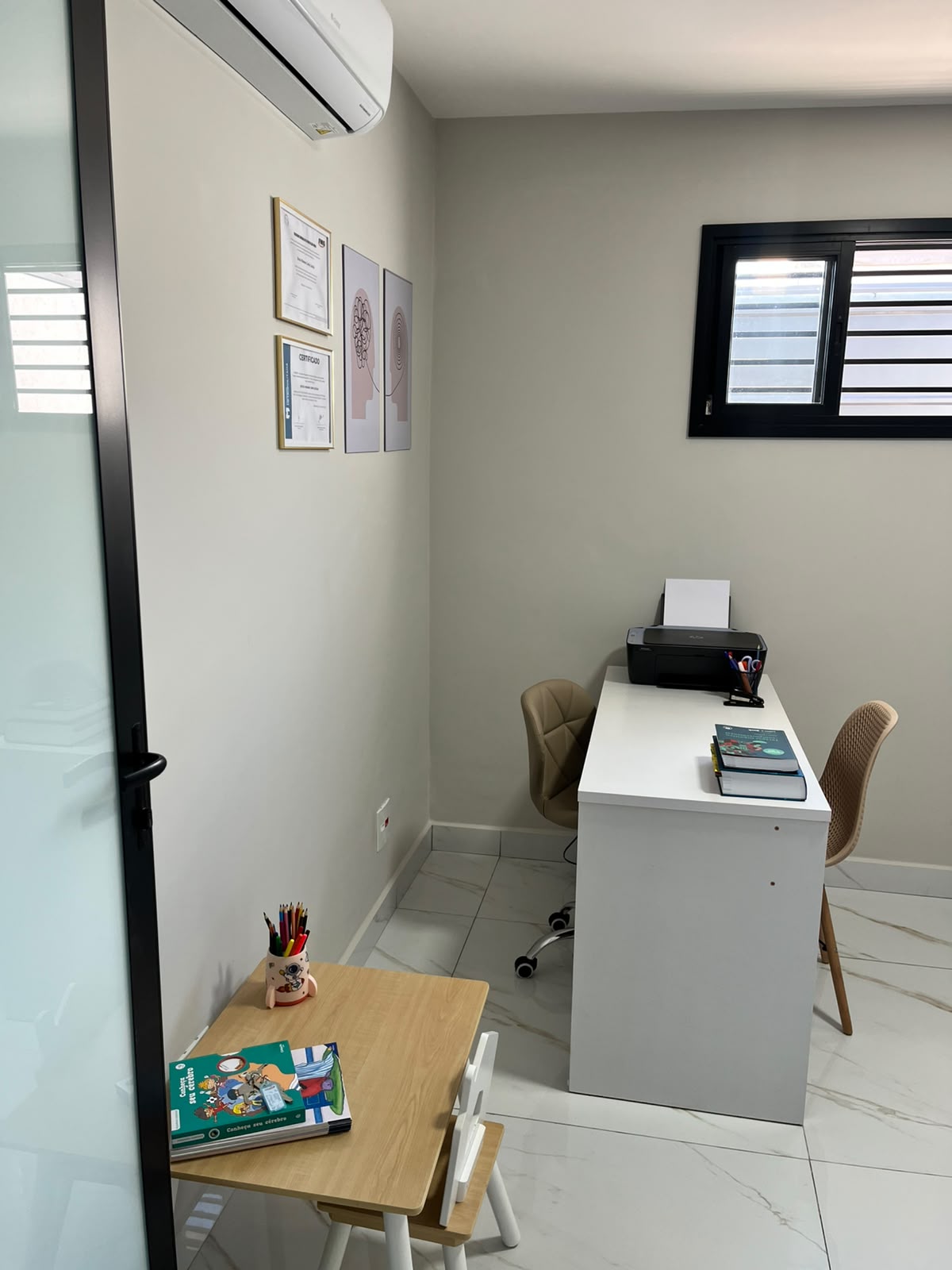 Sala de avaliação neuropsicológica com mesa infantil e certificados na parede